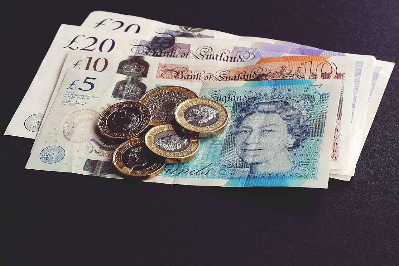 High-quality image of British pound notes and coins on a dark surface, showcasing currency detail.